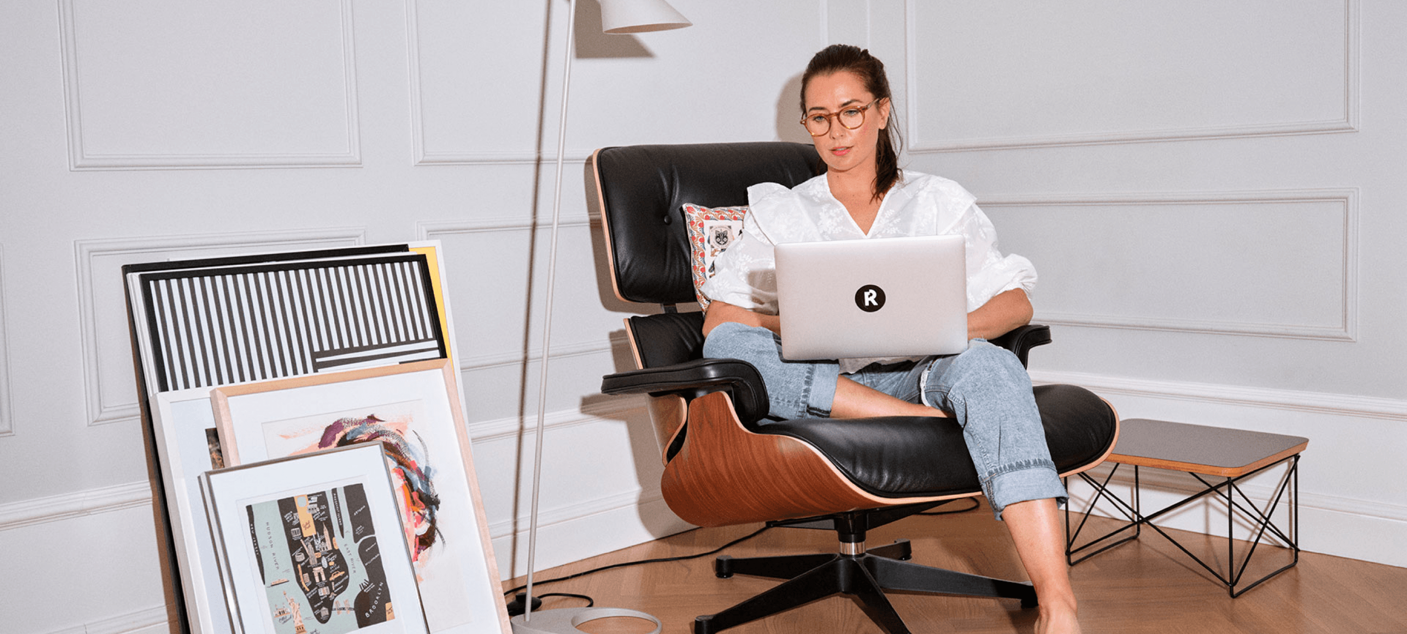 Person sitting down on Eames chair while working on laptop.