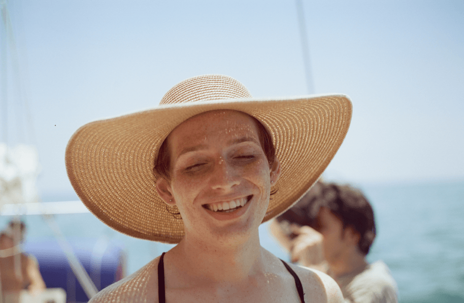 A person on a boat wearing a sun hat with the ocean in the background.