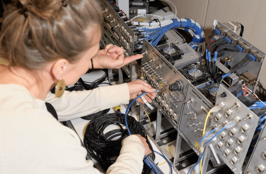 A person plugging a wire into electrical equipment.